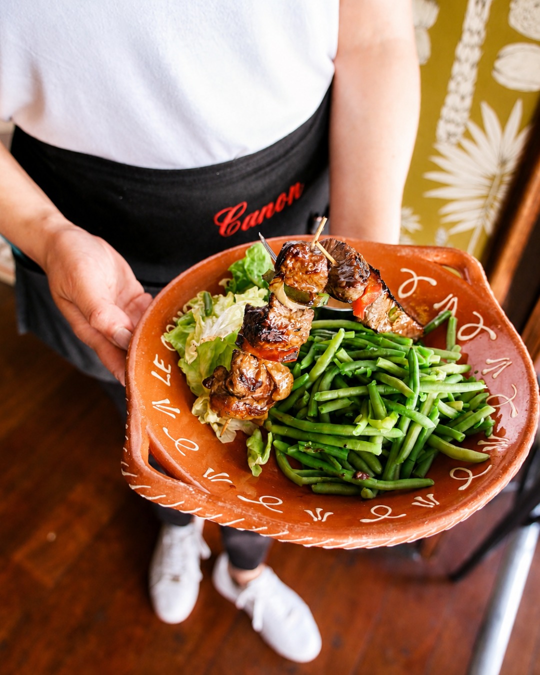Serveuse présentant une brochette accompagnée de haricots verts